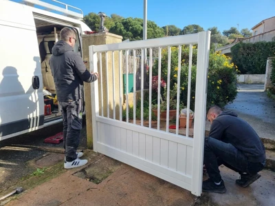 Technicien en combinaison bleue effectuant une intervention de serrurerie sur une porte d'entrée moderne