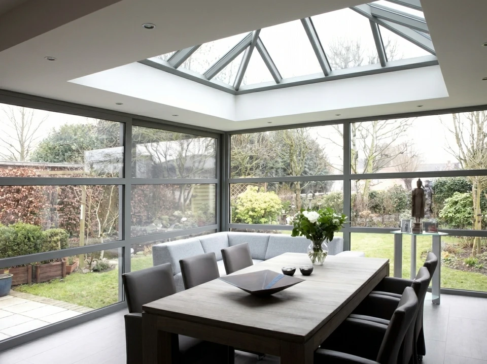 Scène extérieure montrant une pergola moderne avec structure métallique noire et panneaux de protection solaire inclinables
