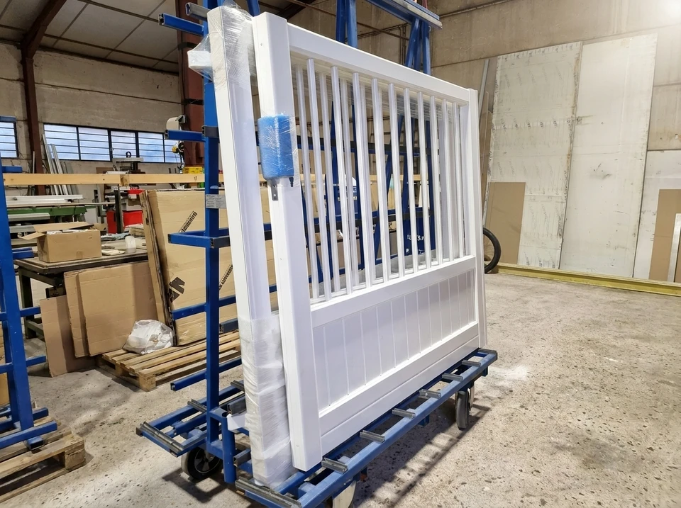 Scène extérieure résidentielle avec portail automatique blanc fermé donnant sur une voie privée goudronnée